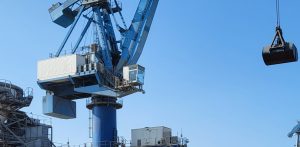 Grue portuaire bleue en opération dans un port industriel avec benne suspendue